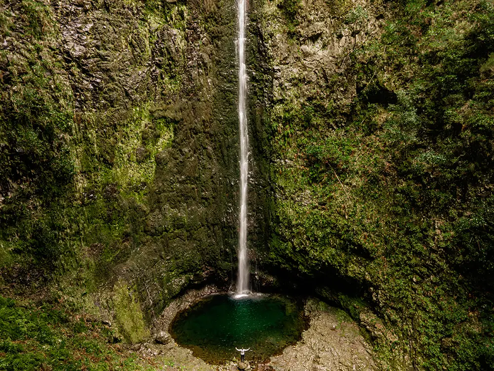 Caldeirao Verde Waterfall cascading down rocky cliffs into a natural pool in Madeira.