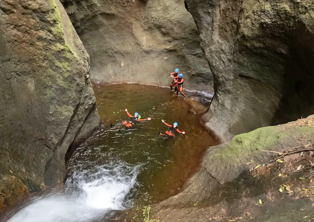 Group of individuals participating in canyoning in a rocky area with water.