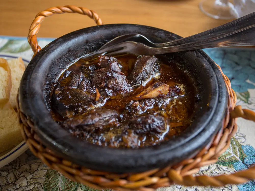 Clay pot containing a traditional meal with pieces of meat and sauce.