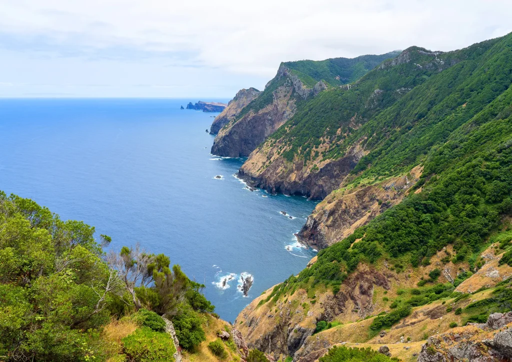 Coastal landscape featuring cliffs and ocean at Boca Risco, with greenery on the slopes.