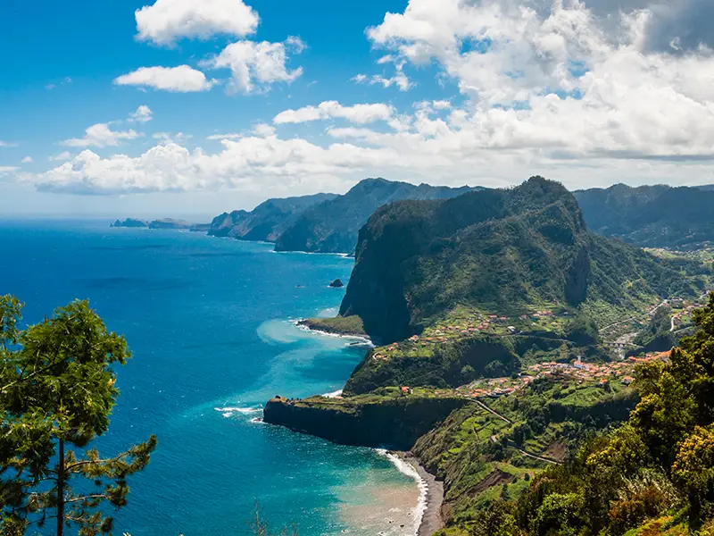 Scenic coastal view of Madeira Island featuring cliffs and ocean waves under a blue sky.