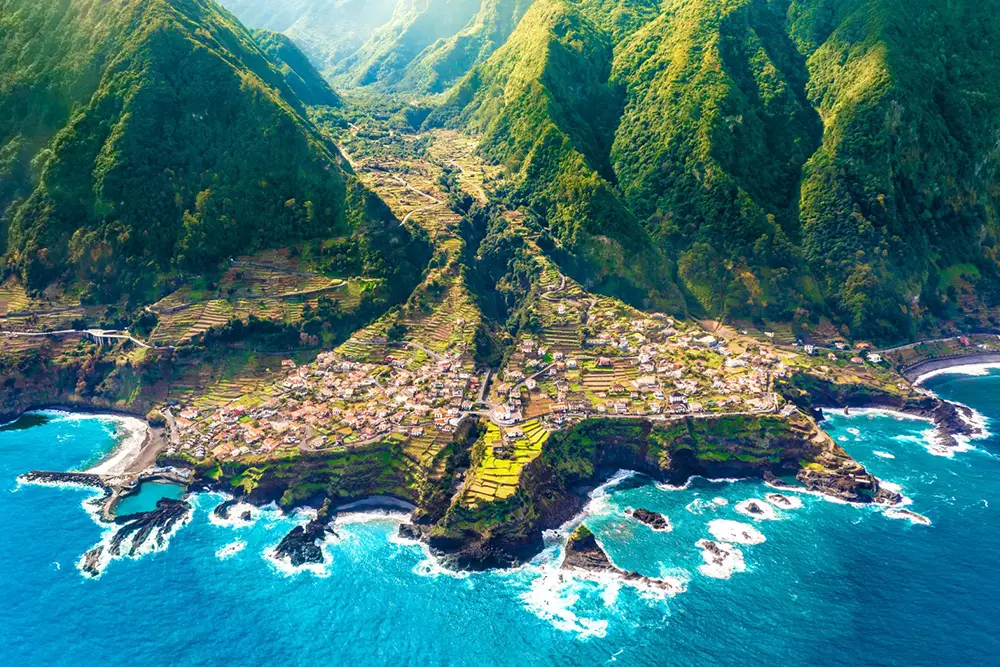 Aerial view of Seixal, a coastal village in Madeira, featuring terraced fields and mountainous terrain.