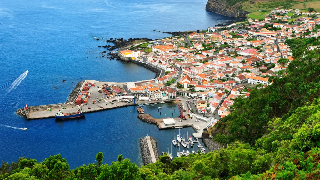 Aerial view of a coastal town featuring a harbor, colorful buildings, and boats in the water.