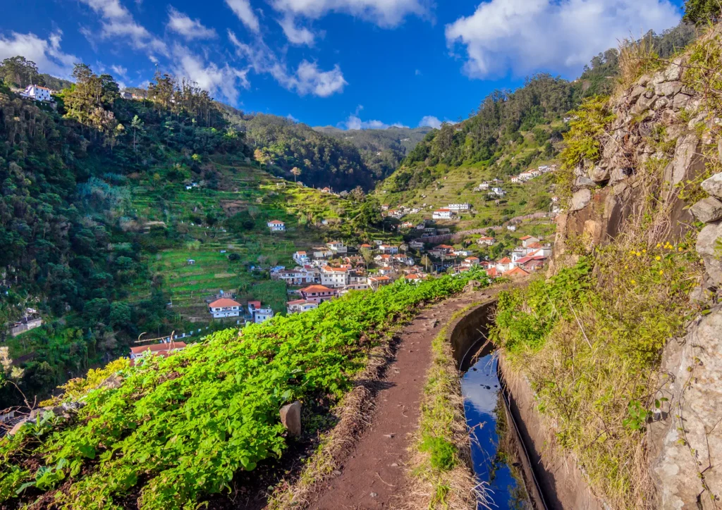 A walking path along green hills with a view of a village in the distance in Morocco.