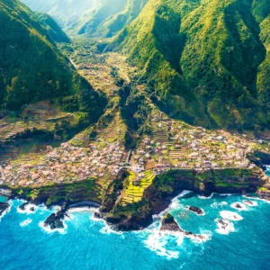 Aerial view of Porto Moniz, a coastal village in Madeira, surrounded by mountains and ocean.
