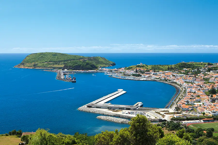 Aerial view of Faial Island showing the harbor and surrounding landscape under a clear blue sky.