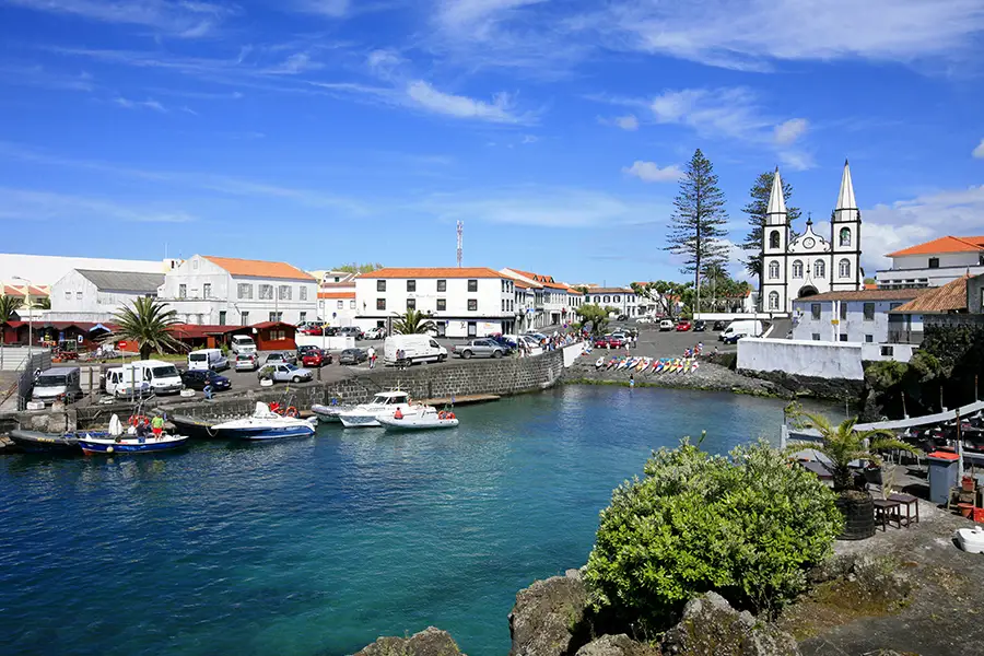 Coastal view of Pico Island featuring boats and a church in the background.